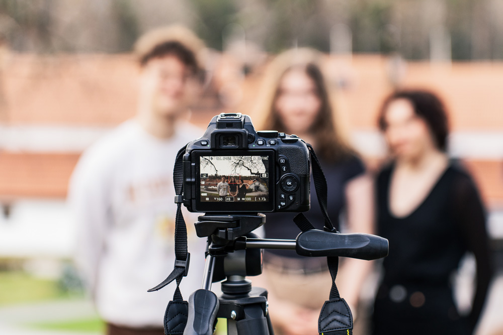 Kolme henkilöä kameran edessä.