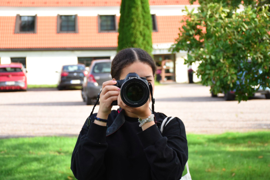 Media-alan opiskelija kuvaa kameralla.